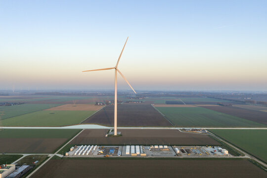 Aerial view of wind turbine generating clean energy, storing electricity in large battery units, promoting sustainable power solutions in the netherlands