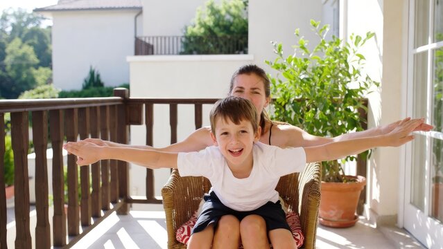 Joyful playtime between mother and son on sunny balcony lifestyle outdoor family bonding
