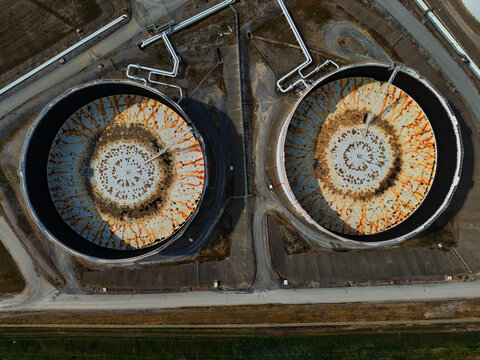 Aerial view of two circular industrial tanks with rust patterns creating abstract art against a backdrop of neutral earth tones, Thessaloniki, Thessaloniki, Greece.