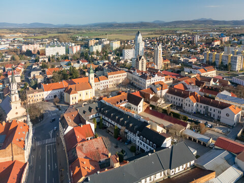 Aerial view of a vibrant city with red rooftops contrasting against modern high-rise buildings, framed by distant mountains, Lucenec, Banska Bystrica Region, Slovakia.