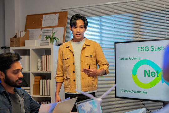 Business team analyzing ESG strategy with presentation on sustainability, renewable energy, and corporate responsibility, discussing data, environmental impact, and green innovation in modern office m