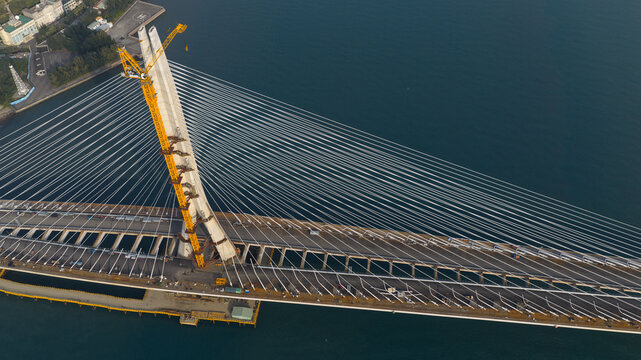 Aerial view of the Tamsui-Tamsui Bridge cable-stayed bridge under construction with its intricate web of cables contrasting against the deep blue waters, Tamsui, New Taipei City, Taiwan.