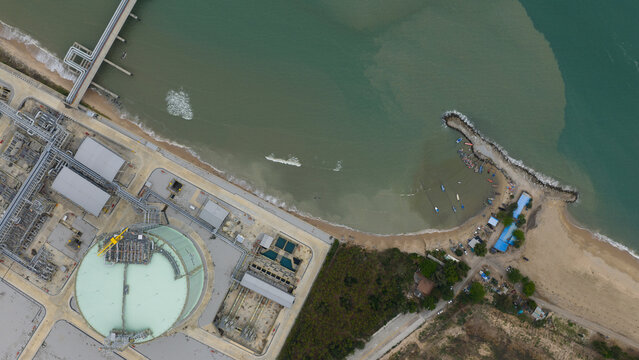 Aerial view of the industrial port where the sea meets the shore, with strong contrast of dark and light, Tambon Map Ta Phut, Chang Wat Rayong, Thailand.