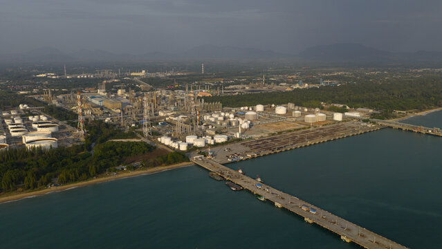 Aerial view of a sprawling industrial complex meets the coastline, where a long bridge cuts across the tranquil waters, Tambon Map Ta Phut, Chang Wat Rayong, Thailand.