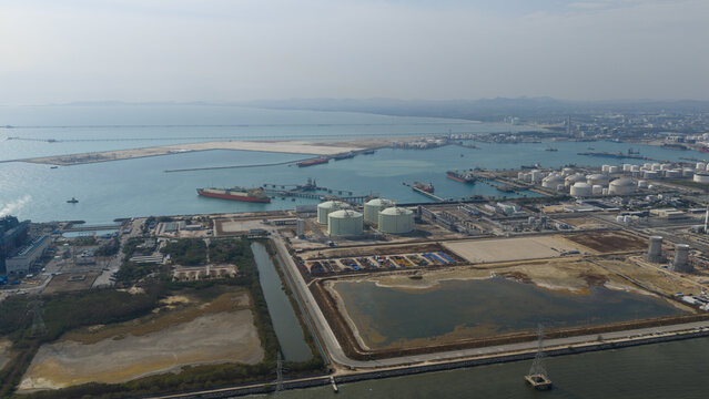 Aerial view of industrial tanks gleaming white against the blue sea and sky, near the Map Ta Phut LNG terminal, Tambon Map Ta Phut, Chang Wat Rayong, Thailand.