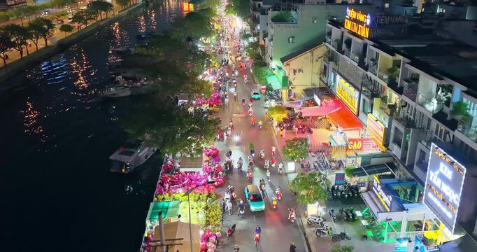 Boats with flowers from Mekong Delta on canal selling at roadside night market Binh Dong Street, Ho Chi Minh city, Vietnam for Lunar New Year