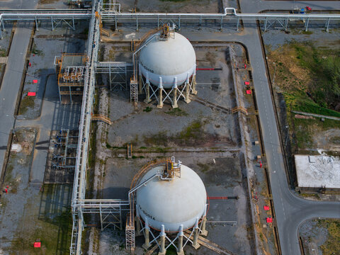 Aerial view of spherical tanks gleaming under the sun, nestled amidst industrial infrastructure, creating a stark contrast between form and function,Thessaloniki, Greece