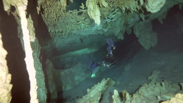 A cave diver approaches a limestone column and air pocket beneath stalactites in a submerged cavern in Cenote Dos Ojos, Mexico
