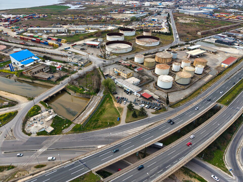 Aerial view of a network of highways weaving past industrial zones and storage tanks under a cloudy sky, Thessaloniki, Thessaloniki, Greece.