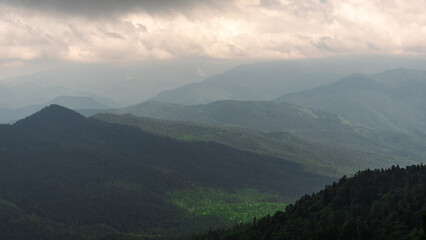 Obraz premium landscape rocky mountains against the sky with clouds and forests with fresh plants in spring in the north