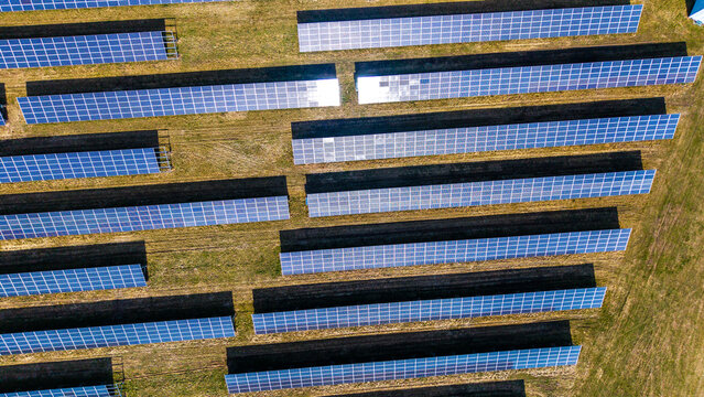 Aerial view of solar panels basking in the sun's glow, creating a geometric pattern against the dry grass, Sevetin, South Bohemian Region, Czechia.