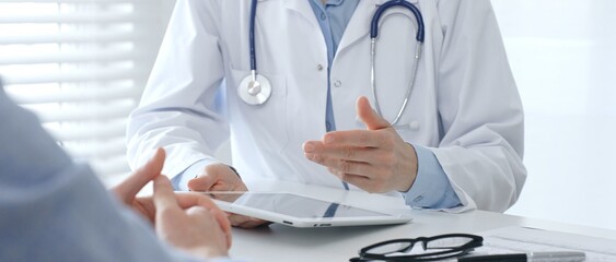 Female doctor explaining diagnosis to her patient during a medical consultation in a bright medical...