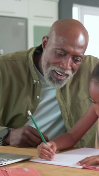Vertical video: Placing green pencil near girl's hand man guiding writing home wearing olive shirt