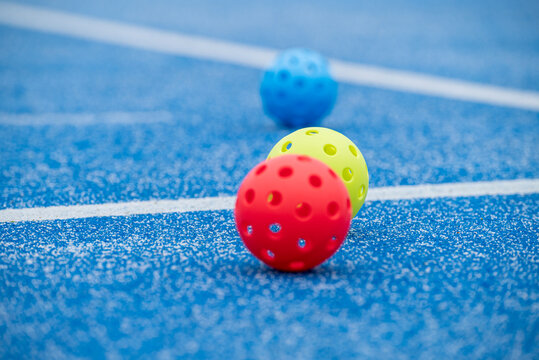 Red yellow and blue floorball balls on a blue sports court with white lines
