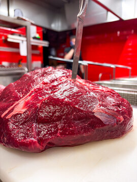 Uncooked Beef Shoulder On Station. Commercial Kitchen Setting With Raw Beef And Trimming Tools Visible