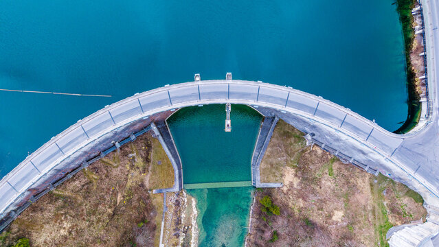 Aerial view of the Staudamm Klaus dam's stark concrete arch contrasts with the serene turquoise waters it holds back, Klaus an der Pyhrnbahn, Oberosterreich, Austria.