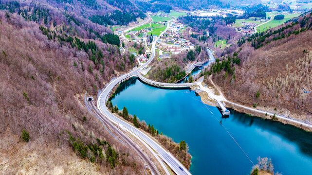 Aerial view of the Klaus Dam's serene blue waters contrast dramatically with the surrounding brown hills and the quaint village, Klaus an der Pyhrnbahn, Oberosterreich, Austria.