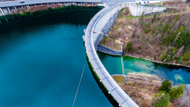 Aerial view of the Staudamm Klaus dam reflecting the sky in its turquoise waters, a concrete curve against the autumnal landscape, Klaus an der Pyhrnbahn, Oberosterreich, Austria.
