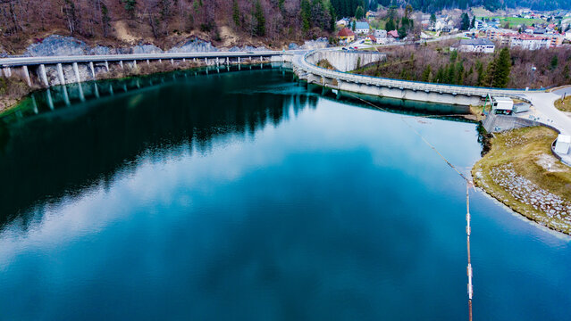 Aerial view of the Staudamm Klaus dam reflecting the sky's hues, contrasting with the surrounding verdant hills, Klaus an der Pyhrnbahn, Oberosterreich, Austria.