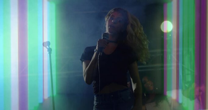 Beat dropping, lead singer whipping hair, bobbing, bringing mic closer, performing amid LED lights