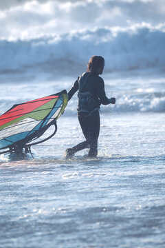 Cascais, Portugal - 28 March 2026: View of a windsurfer silhouetted against massive crashing waves at Praia do Guincho with white sea foam and deep blue water.