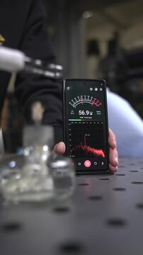 Vertical video about the thermoacoustic effect: The scientist inserts metal wool into a flask, wraps a piece of wet cloth around the flask, lights the wick of an alcohol lamp and brings it to the flas