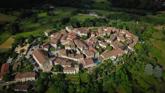 Aerial view of the medieval village of Perouges, with its old stone buildings clustered tightly together, surrounded by lush green trees., Perouges, Auvergne-Rhone-Alpes, France.