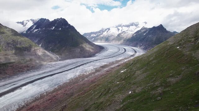 Aerial 4k drone view of the Aletsch Glacier revealing thinning ice, exposed debris, and flowing ice patterns, illustrating glacier retreat and the visible impact of climate change in the Swiss Alps.