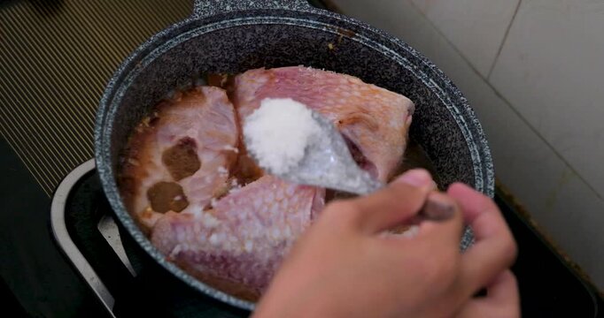 Vietnamese red fish cooking in gray pan with chili garlic and salt simmering on gas stove showing traditional soup preparation step by step