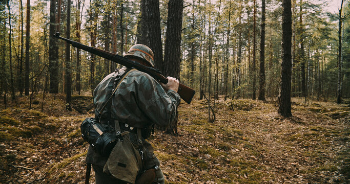 Rear view of German soldier walking into forest with rifle during WWII