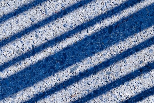 diagonal  lines from shadows of a fence on a sidewalk 