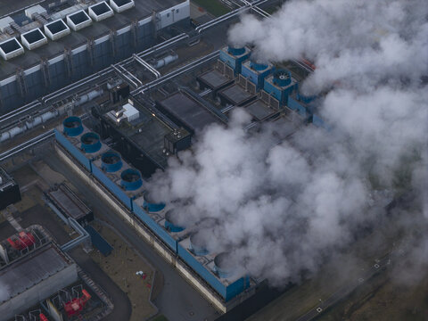 Aerial view of a large data center complex in eemshaven, netherlands, with cooling towers releasing steam into the atmosphere