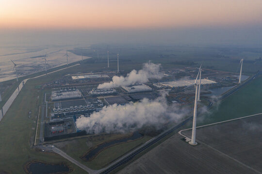 Aerial view of cloud computing and ai infrastructure operating in eemshaven, netherlands, powered by renewable energy from surrounding wind turbines