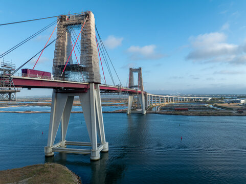 Aerial view of the Ponte Edgar Cardoso bridge with its stark concrete pillars and vibrant red accents contrasting against the deep blue waters below, Figueira da Foz, Coimbra District, Portugal.