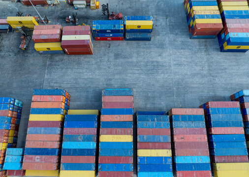 Aerial view of stacks of multicolored shipping containers casting stark shadows on the concrete landscape of the port, Figueira da Foz, Coimbra District, Portugal.