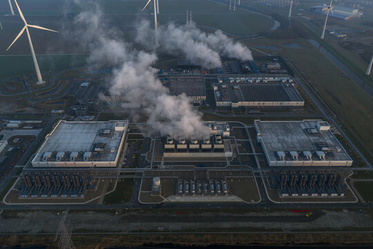 Aerial view of large data center processing vast amounts of data for cloud computing and artificial intelligence, powered by surrounding wind turbines in netherlands