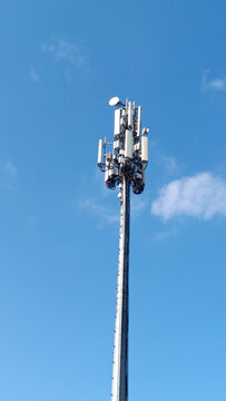 A modern telecommunication cell tower (BTS) with antennas and transmitters against a clear blue sky. Concept of 5G, mobile network, signal coverage, and wireless technology