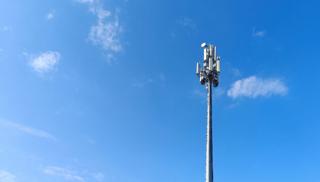 A modern telecommunication cell tower (BTS) with antennas and transmitters against a clear blue sky. Concept of 5G, mobile network, signal coverage, and wireless technology