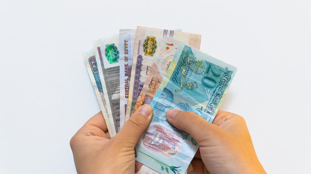 Hands holding egyptian pound banknotes, illustrating financial concepts like inflation, spending, and savings