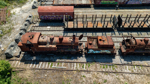 Aerial view of decaying locomotives and train cars sit rusting on tracks, a symphony of aged metal and forgotten journeys, Vila Nova de Gaia, Portugal.