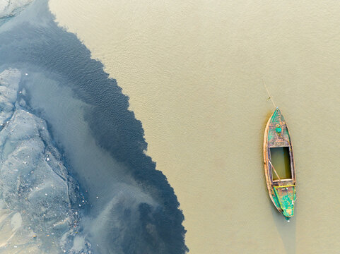 Aerial view of contrasting waters meet in a swirl of colors, where a lone boat floats serenely, Chattogram, Chittagong Division, Bangladesh.