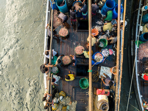 Aerial view of boats filled with bustling activity, a symphony of colors and textures as people sort and trade their wares, Chattogram, Chittagong Division, Bangladesh.