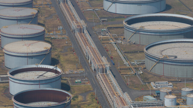 Aerial view of sprawling oil tanks glinting under the sun, connected by a network of metallic pathways at Dalin refinery, Kaohsiung City, Taiwan.