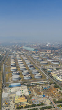 Aerial view of rows of gleaming white storage tanks contrasting against the industrial landscape under a clear sky, Kaohsiung City, Taiwan.