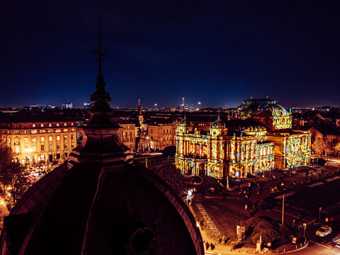 Aerial view of the Croatian National Theater illuminated with bright, colorful projections against the dark night sky, Zagreb, Croatia.