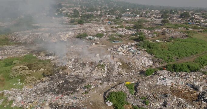 Aerial fly over view. Burning rubbish causing greenhouse gas, contributor to climate change.  Extreme Poverty. People living alongside dumpsite struggling to survive through waste picking.