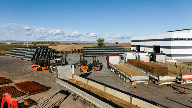 Aerial view of the industrial site with the trucks and forklifts surrounded by fields under the expansive sky, Sremska Mitrovica, Vojvodina, Serbia.