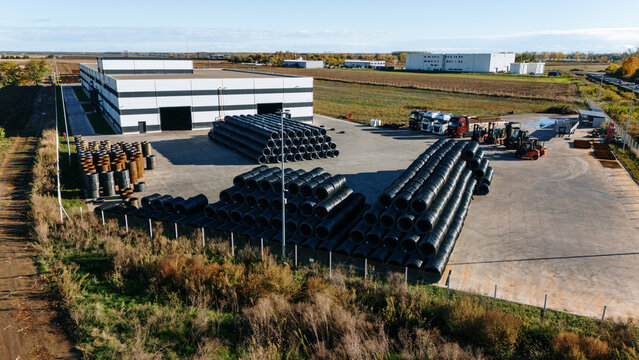 Aerial view of neatly stacked coils of steel contrasting with the angular architecture of industrial buildings, Sremska Mitrovica, Vojvodina, Serbia.