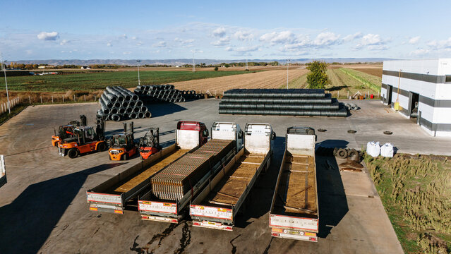 Aerial view of a logistics hub with trucks and equipment bathed in the warm sunlight, casting long shadows across the concrete in Sremska Mitrovica, Vojvodina, Serbia.