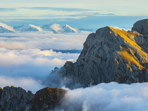 Aerial view of Puez range peaks piercing through a sea of clouds, the Dolomites stand majestic against the horizon, Dolomites, Trentino-Alto Adige, Italy.